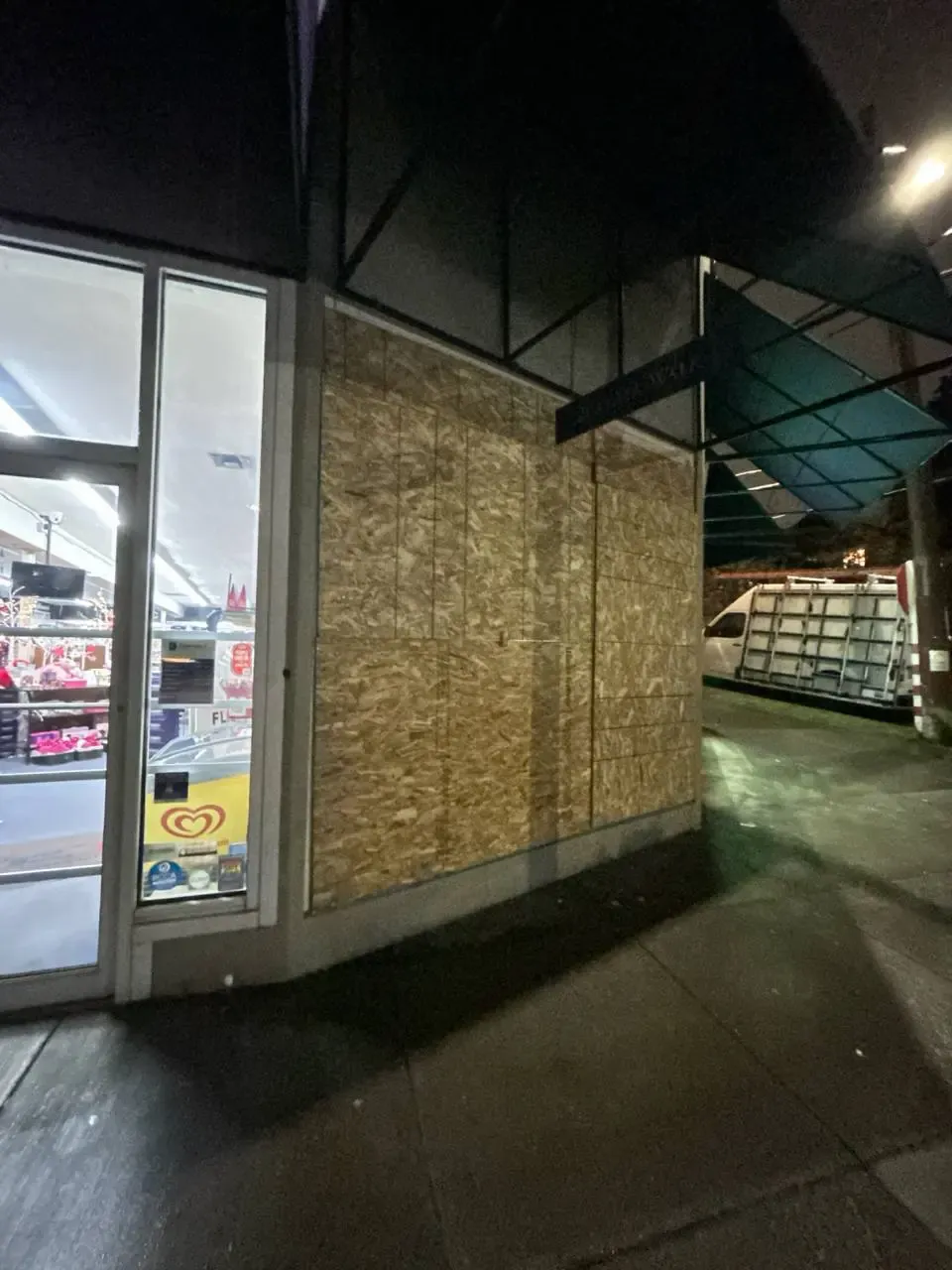 Storefront window covered with wood panels at night