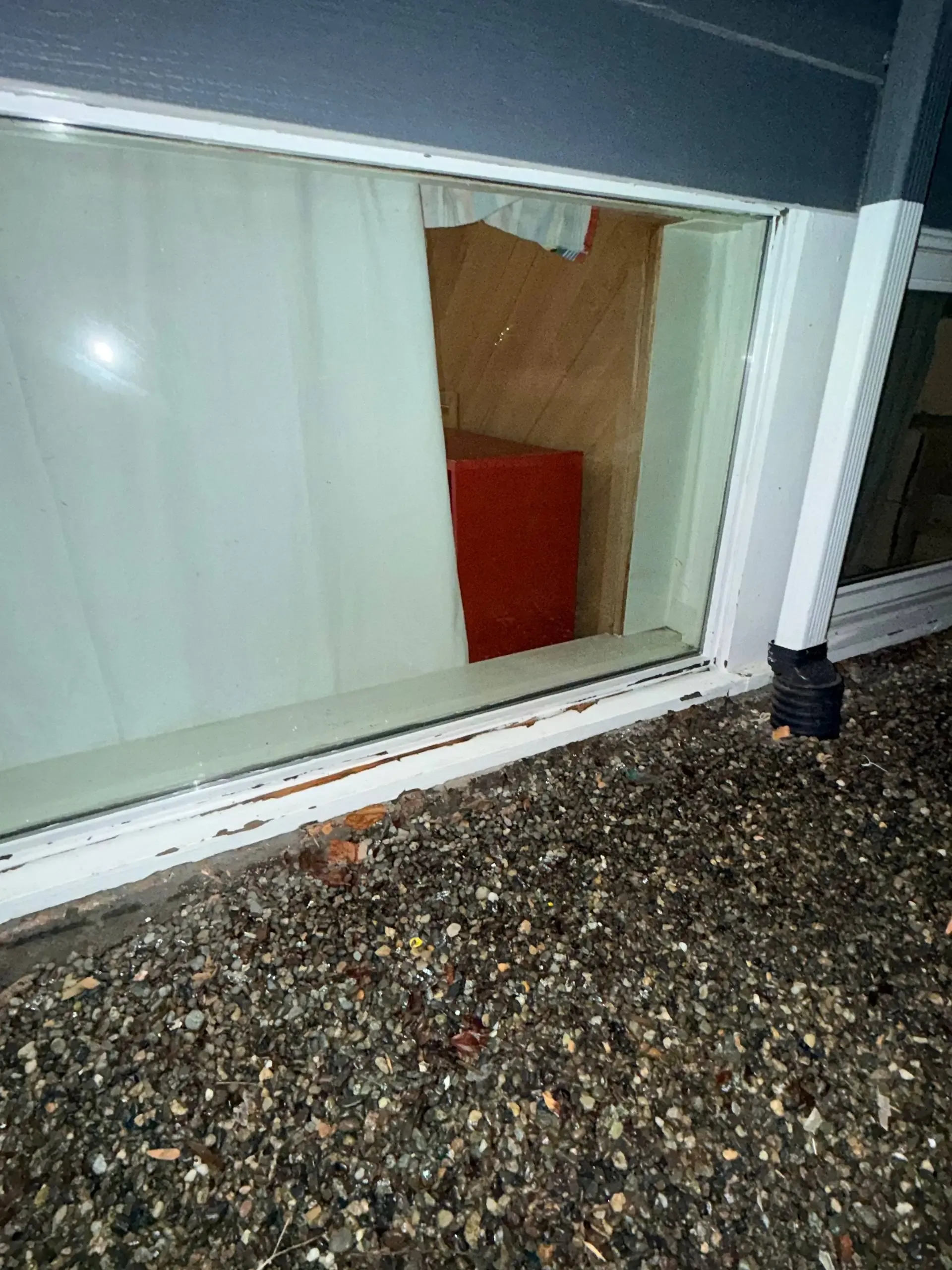Exterior view of a clear window pane in an existing white frame with worn paint.