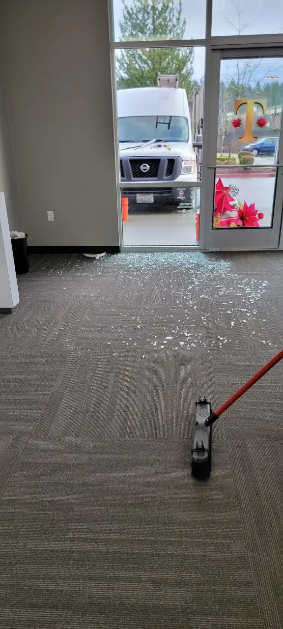 Glass fragments on a floor near a storefront entrance during cleanup