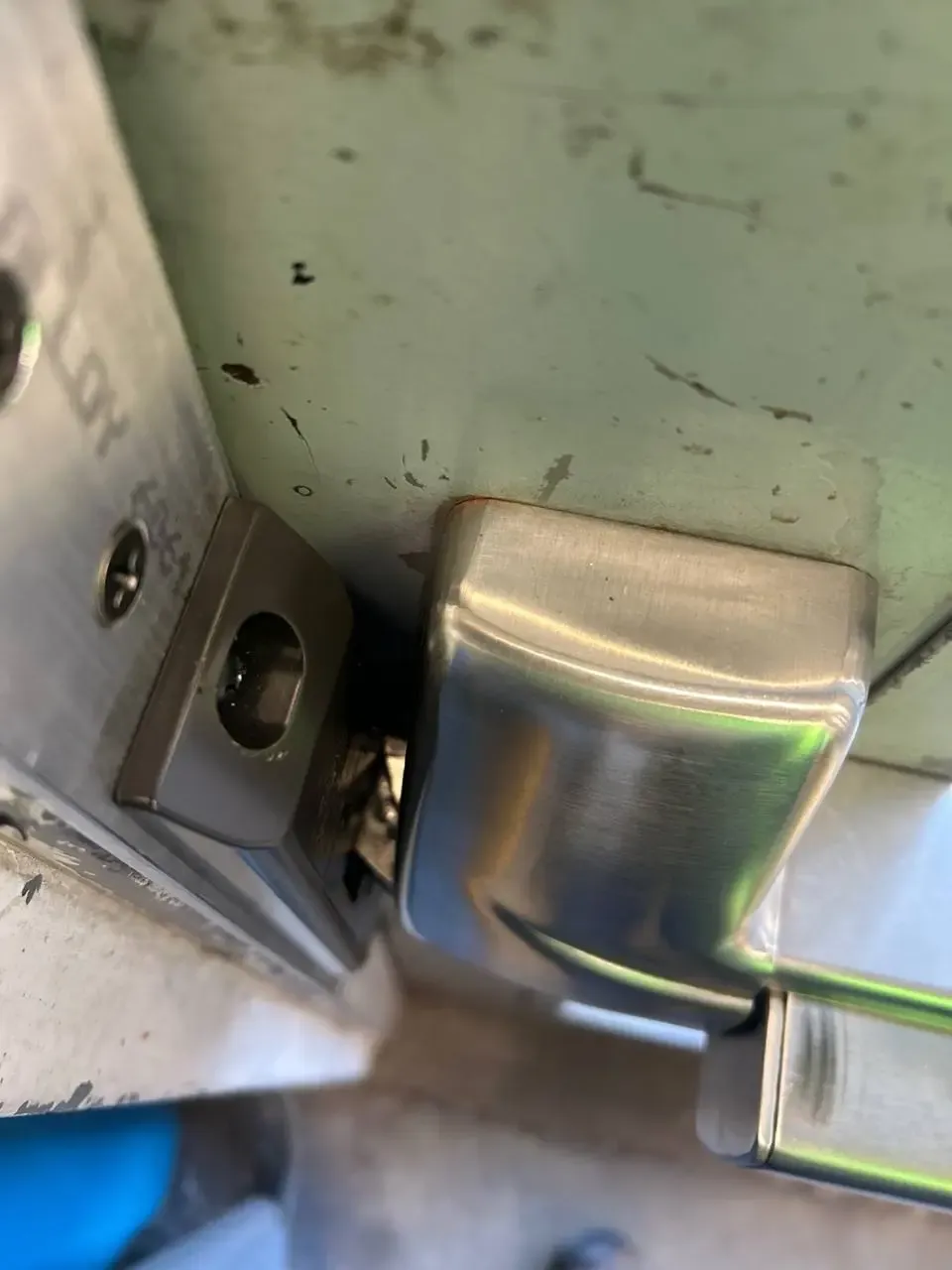 Close view of damaged commercial door latch hardware beside the strike plate