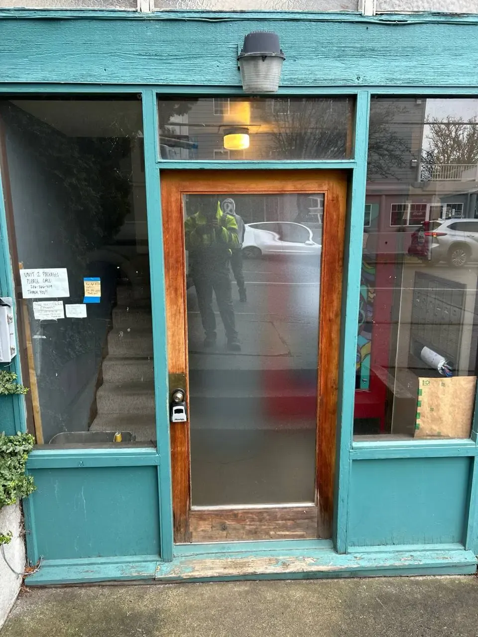A glazed timber entrance door within a turquoise-painted storefront.