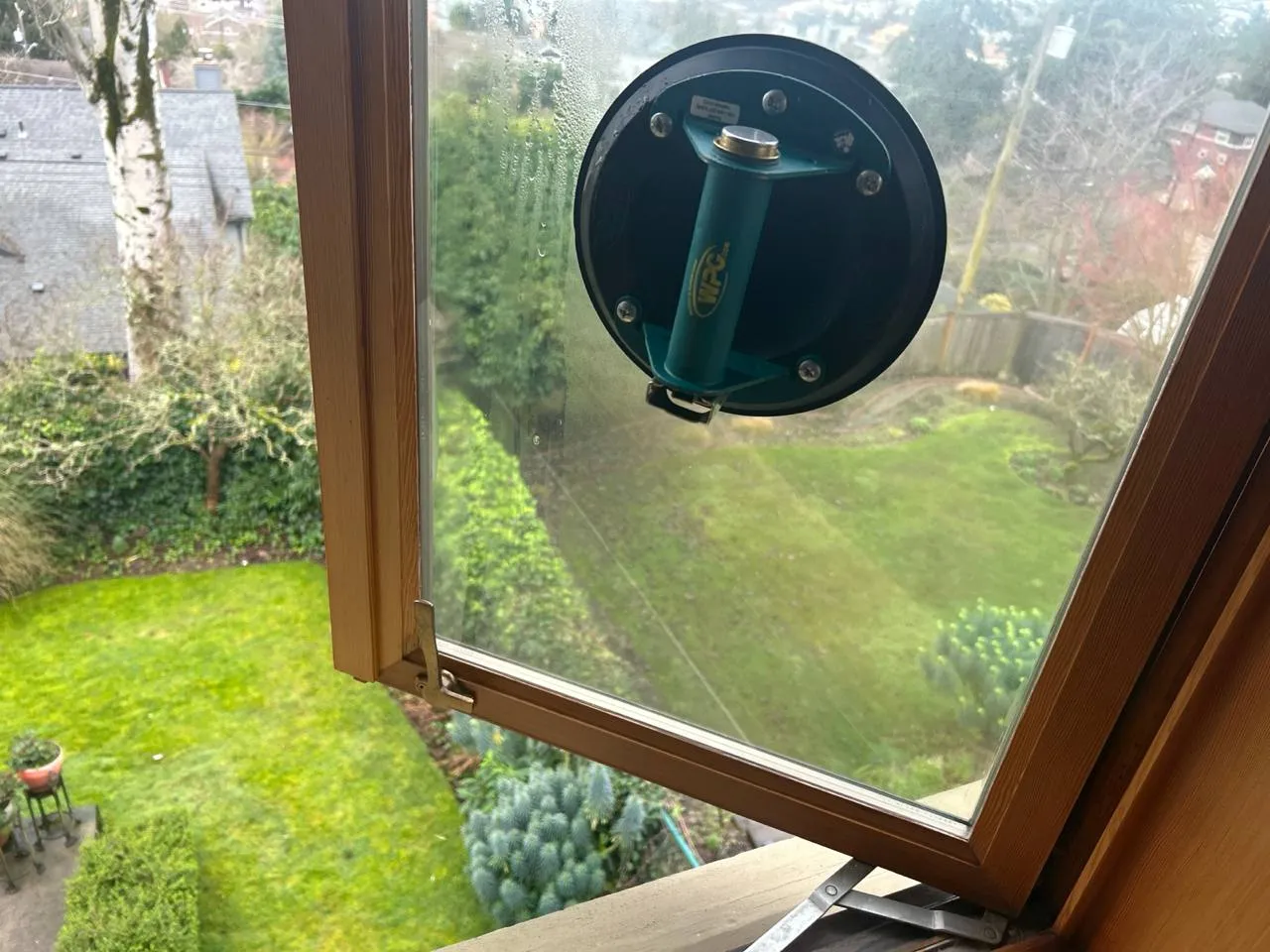 A suction handle attached to a pane in an open timber window.