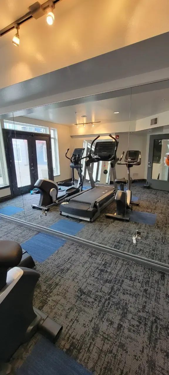 A tall mirrored wall reflecting exercise equipment, with panel joints visible.