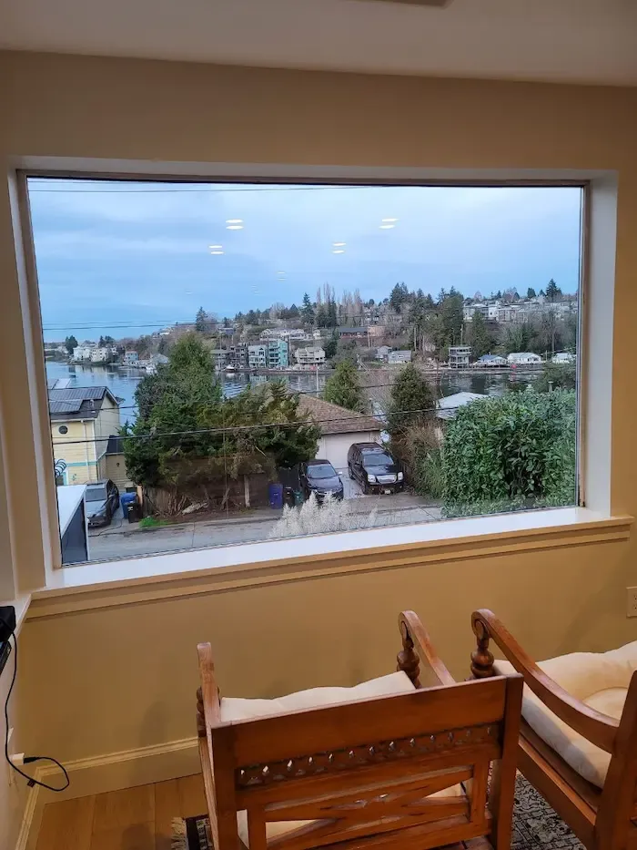 Large picture window overlooking homes, trees, and water.