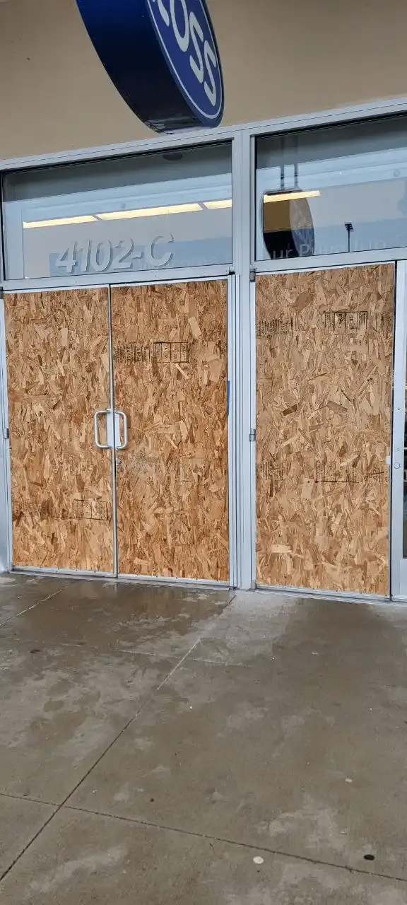 Commercial storefront doors and windows temporarily secured with wood panels