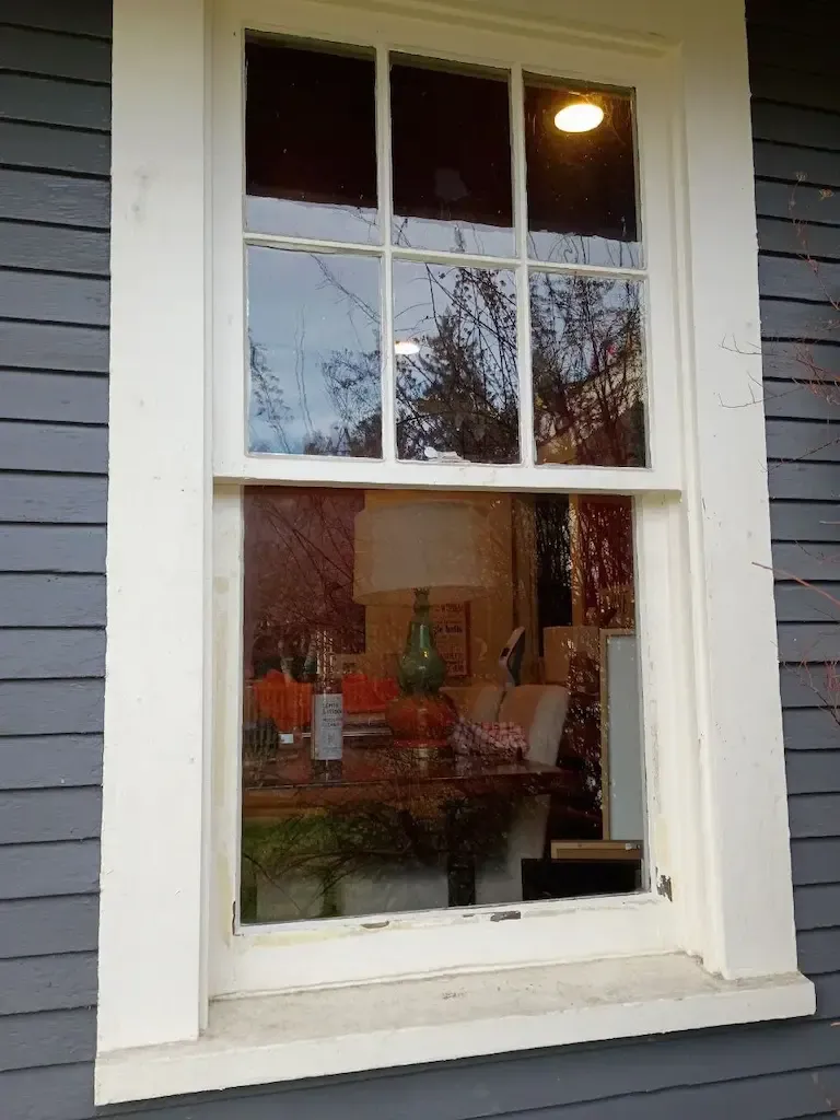 White-painted wood window with divided upper panes and a large lower pane