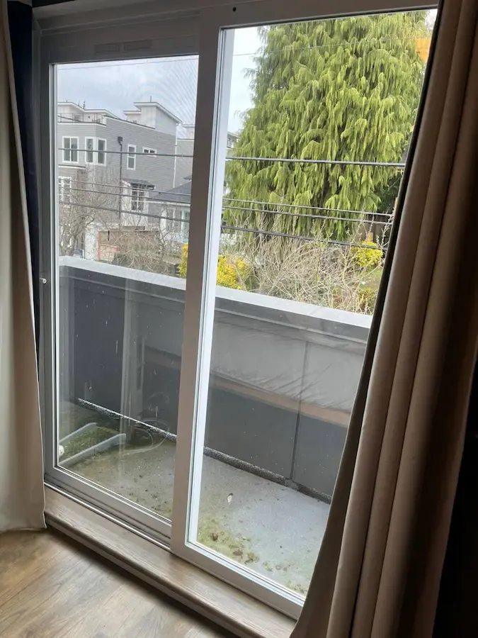 White-framed sliding patio door viewed from inside beside a balcony