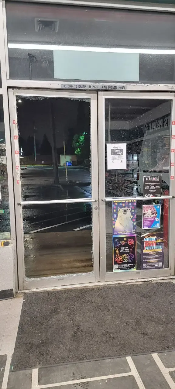 Glass entrance doors with a shattered pane and fragments along the frame