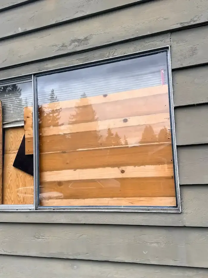Exterior window with wood boards visible behind the remaining glass