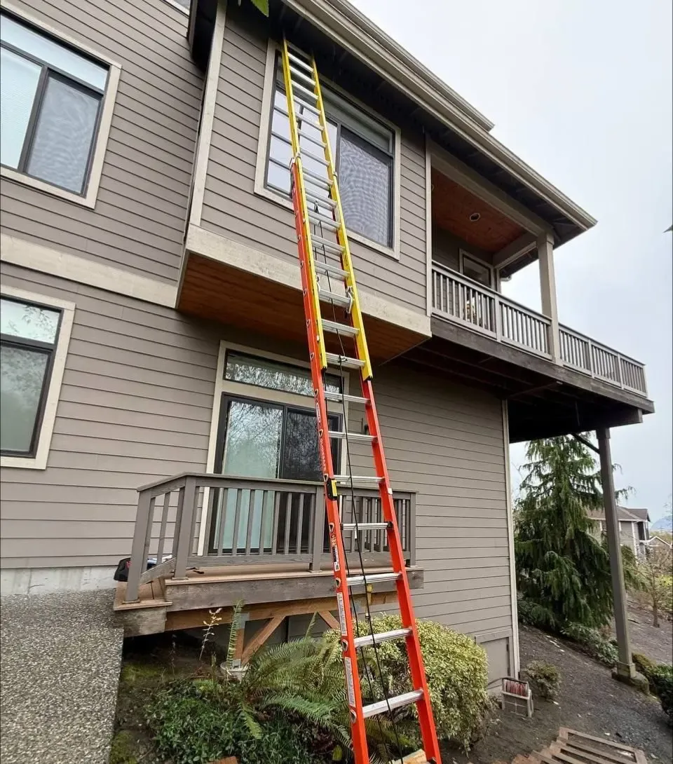 Multilevel house with windows, balconies and an extension ladder against the exterior