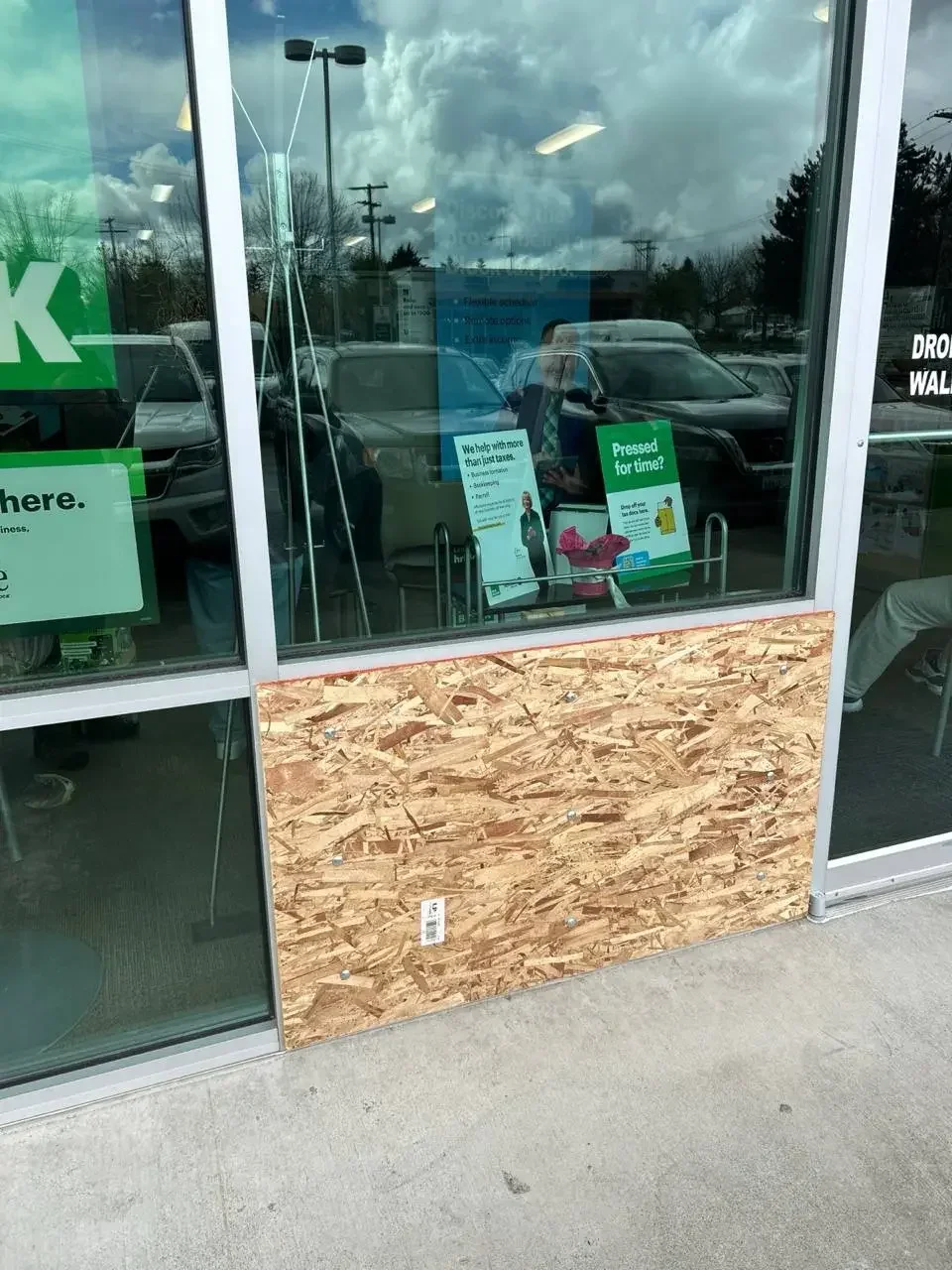 Timber board covering the lower section of a shopfront beside a glazed entrance.