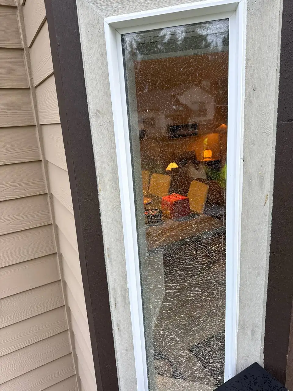 Shattered glass remaining within a narrow residential window frame.