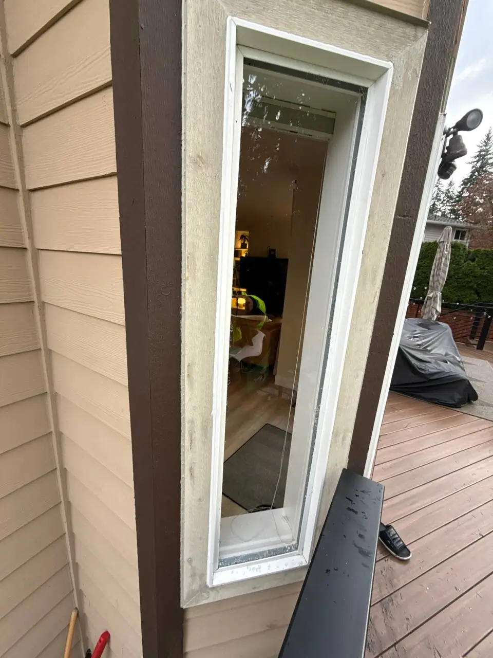 Narrow white window opening photographed at an angle beside exterior siding.